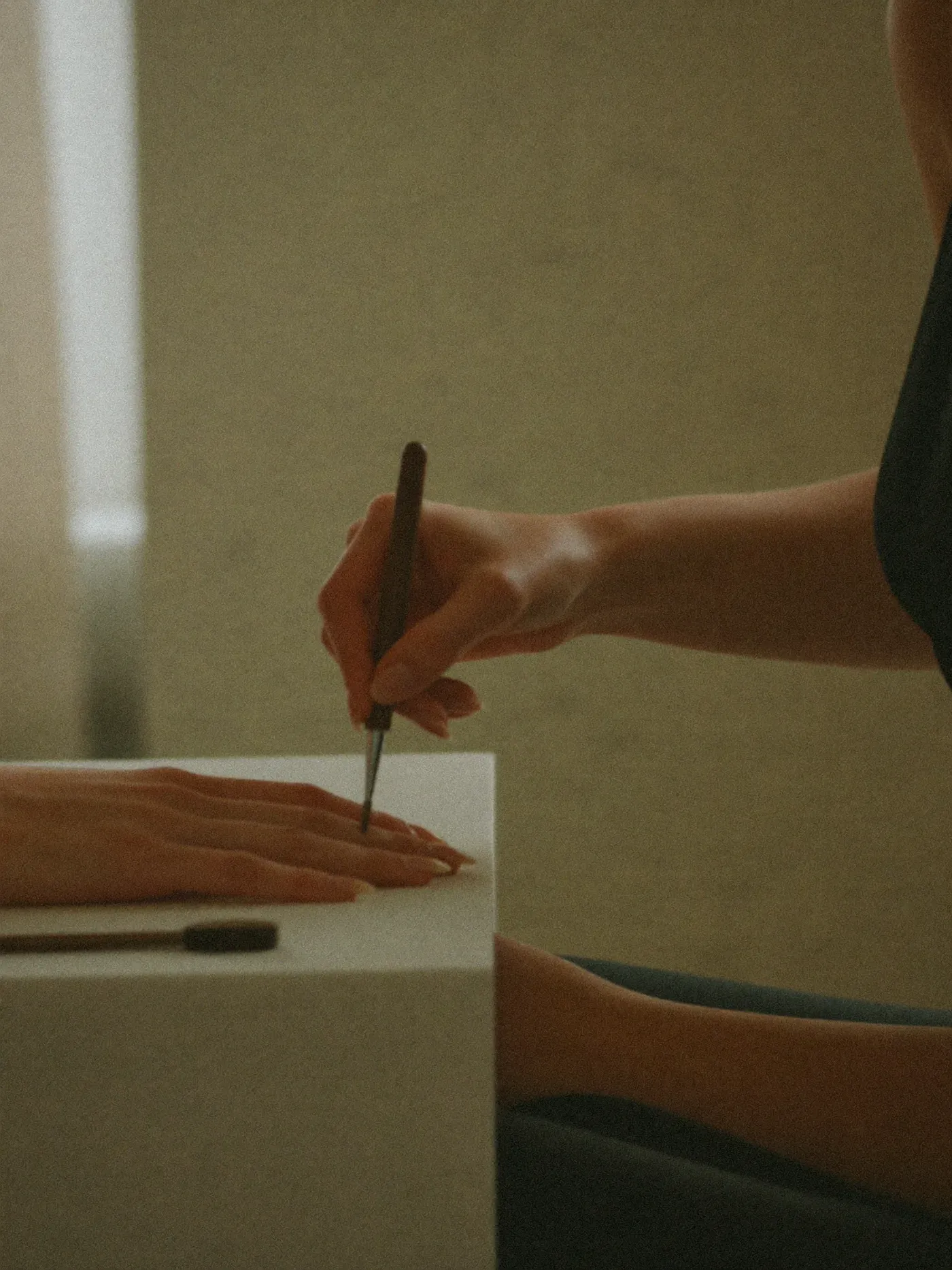 A manicurist working with precision in a warm, minimalist salon